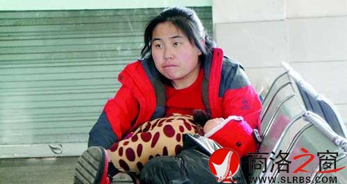 候車廳里，一位母親抱著睡著的孩子發(fā)呆